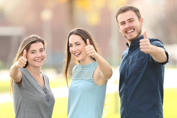 Three people gesturing thumbs up in the street — Stock Photo, Image