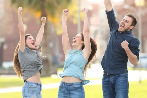 3 amici gioiosi che saltano festeggiando il successo in un parco — Foto Stock