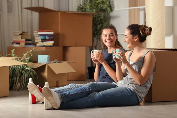 Felices compañeros de piso mudándose a casa descansando y hablando — Foto de Stock