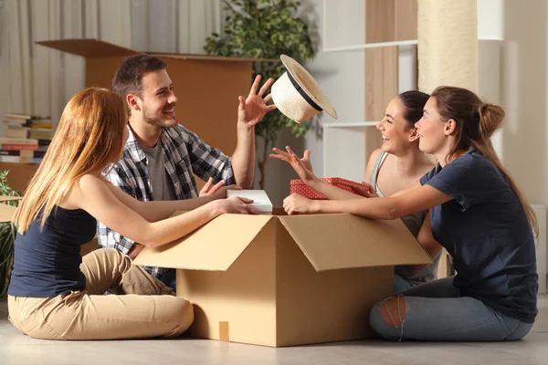 Colegas de quarto felizes brincando unboxing pertences que se mudam para casa — Fotografia de Stock