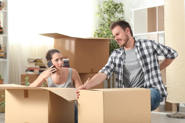 Man suffering an accident moving home and wife calling doctor — Stock Photo, Image