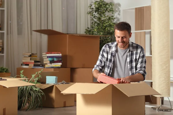 Homem feliz movendo para casa unboxing pertences na noite — Fotografia de Stock