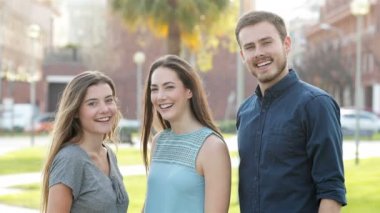 Sokakta kamera da başparmak gesturing üç arkadaş ön görünümü