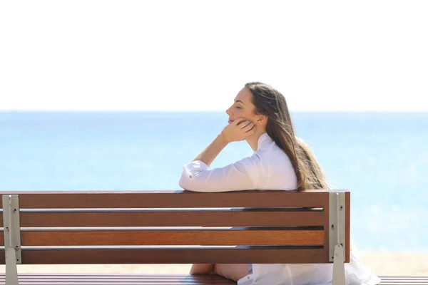 Vrouw ontspannen zittend op een bankje op het strand — Stockfoto