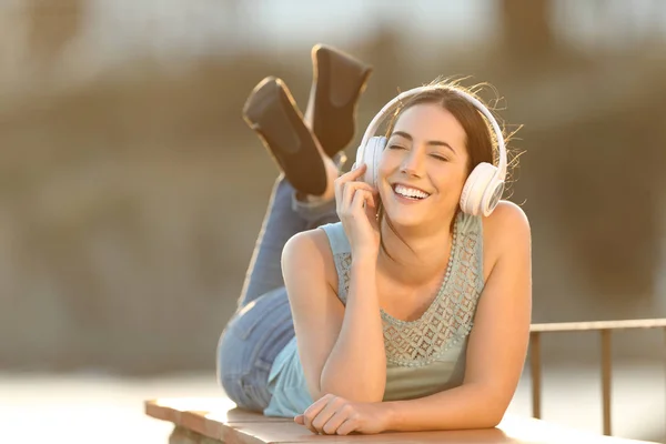 Chica feliz escuchando música con auriculares en una cornisa —  Fotos de Stock