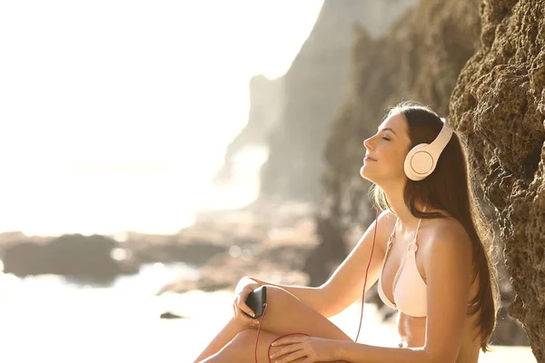 Розслаблений сонячний промінь слухає музику на пляжі — стокове фото
