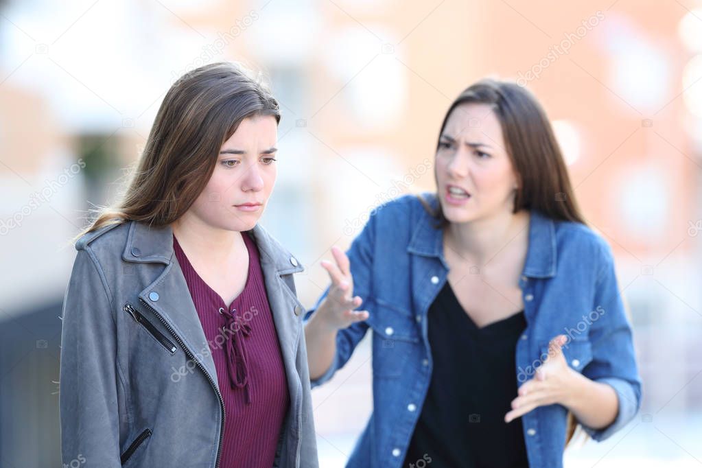 Angry woman scolding her guilty friend