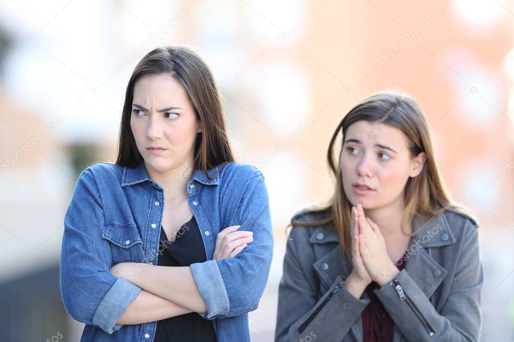 Regretful girl asking forgiveness to her angry friend