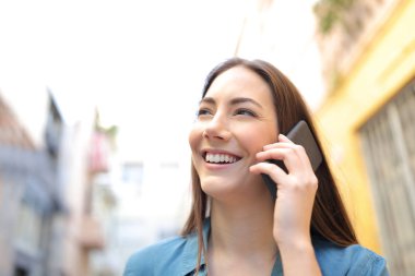 Sokakta cep telefonuyla konuşan mutlu kadın