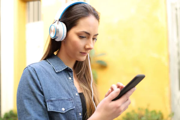 Mulher caminha ouvindo música selecionando música — Fotografia de Stock