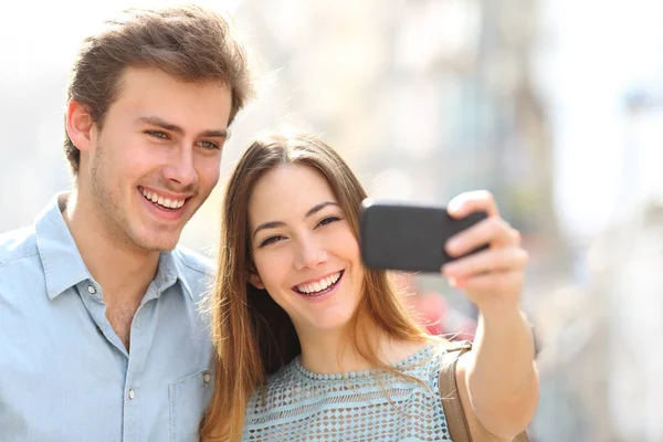 Pareja feliz tomando selfies usando el teléfono en la calle — Foto de Stock