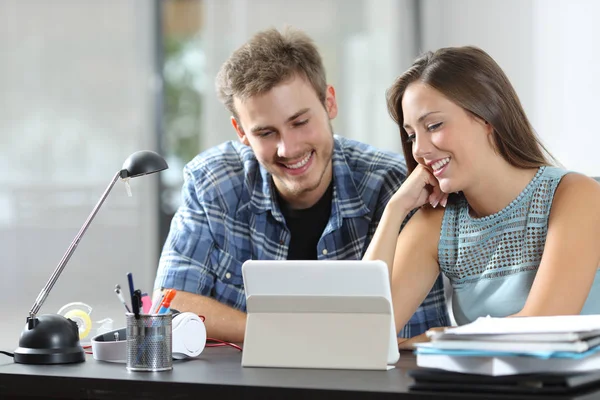 Happy couple watching tablet content on a desk at home — Stock Photo, Image