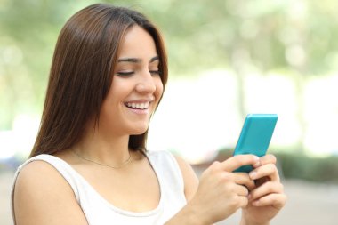 Mutlu genç sokakta yürüyen akıllı telefon kontrol eder