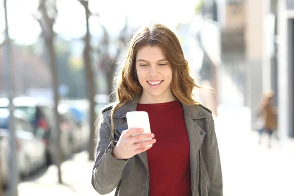 Mutlu genç kız akıllı telefon kullanarak yürüyor — Stok fotoğraf