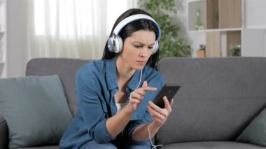 Kızgın kadın evde bir kanepede oturan çöktü telefon kullanarak müzik dinlerken