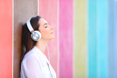 Relaxed girl listens to music in a colorful street clipart