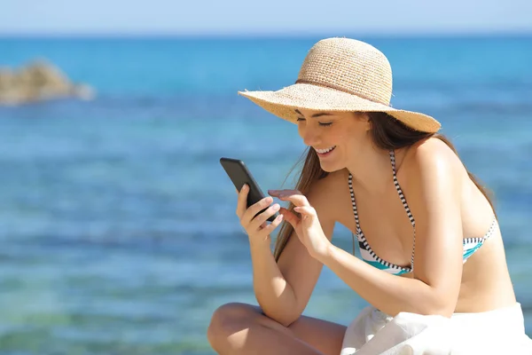 Bagnare il sole felice utilizzando lo smartphone sulla spiaggia — Foto Stock