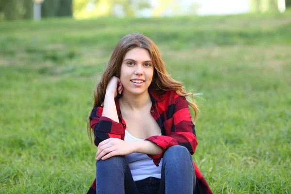 Девочка-подросток смотрит в камеру, сидя на траве — стоковое фото