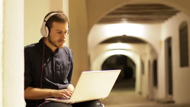 Serious Man Using Laptop Headphones Sitting Town Street Night — Stock Video