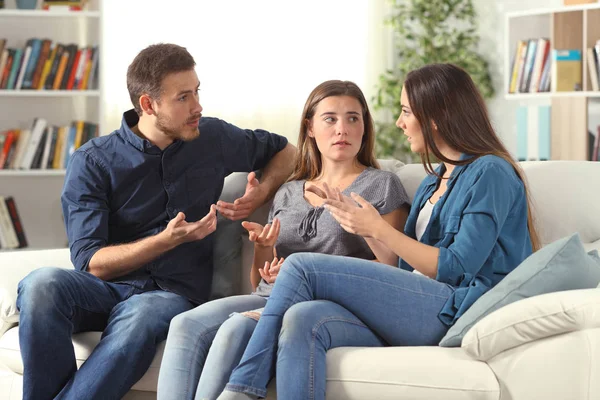 Tiga teman serius berbicara sambil duduk di sofa di rumah — Stok Foto