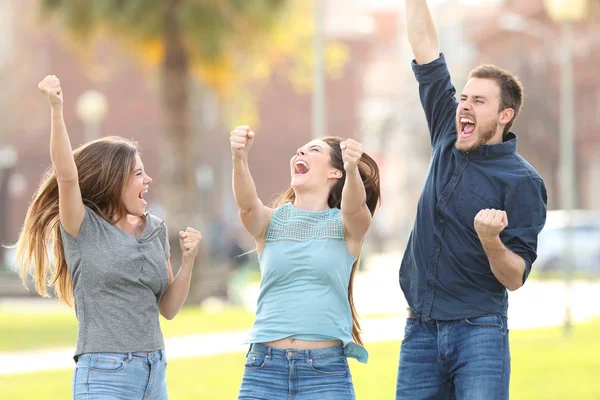 Tre amici entusiasti che saltano festeggiando il successo in un parco — Foto Stock