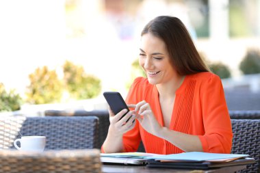 Mutlu girişimci bir bar terasında akıllı telefon kullanır