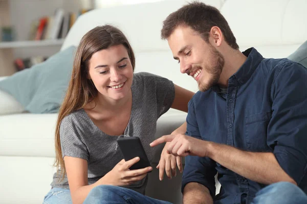 Happy couple checking smart phone apps at home — Stock Photo, Image