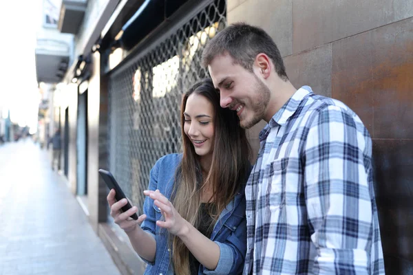 Pareja hablando de contenido en línea de teléfonos inteligentes en la calle — Foto de Stock