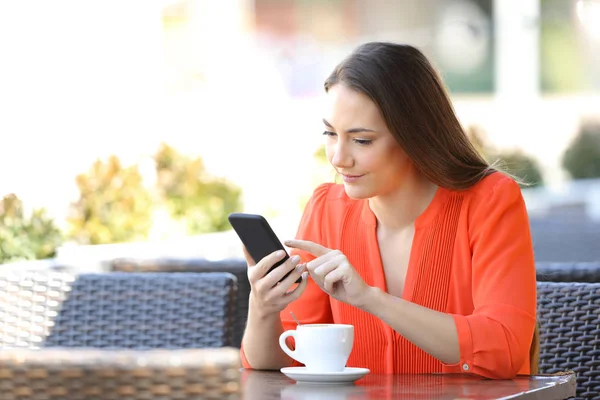 Ciddi kadın bir kafede bir akıllı telefon tarama — Stok fotoğraf