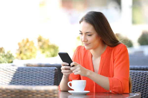 Serious woman is using a smart phone in a coffee shop — Stock Photo, Image