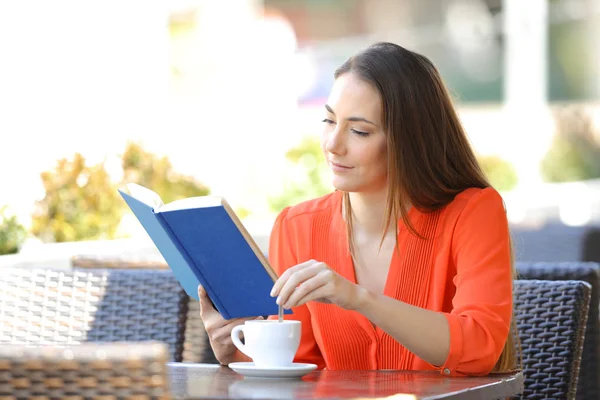 Ciddi bir kadın bir barda kahve karıştırma bir kitap okuma — Stok fotoğraf