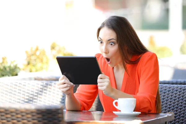 Mulher chocada assistindo e ouvindo mídia em tablet — Fotografia de Stock