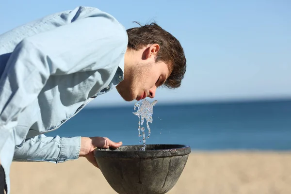 Mann trinkt Wasser aus einem Brunnen am Strand — Stockfoto