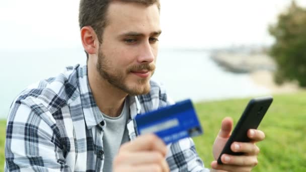 一个男孩用信用卡和智能手机在户外在线支付的特写 — 图库视频影像