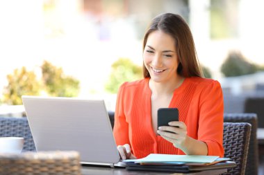 Mutlu girişimci bir kafede birden fazla cihaz kullanarak