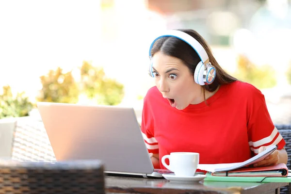 Amazed student e-learning in a coffee shop — Stock Photo, Image