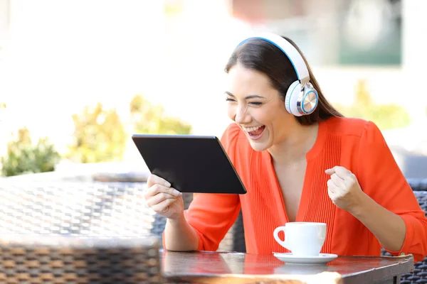 Podekscytowany kobieta oglądanie i słuchanie multimediów na tablecie — Zdjęcie stockowe