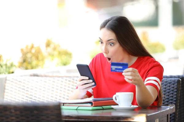 Shocked student paying online with credit card in a bar — Stock Photo, Image