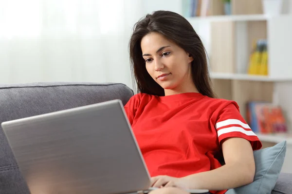 Adolescente usando um laptop em um sofá em casa — Fotografia de Stock