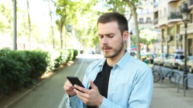 Sokakta akıllı telefon kullanan memnun olmayan adam hayır diyerek ve bir süre sonra kameraya bakıyor