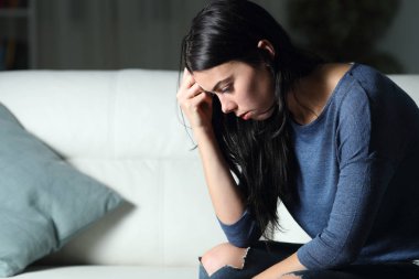 Endişeli kadın gece evde tek başına düşünüyor.