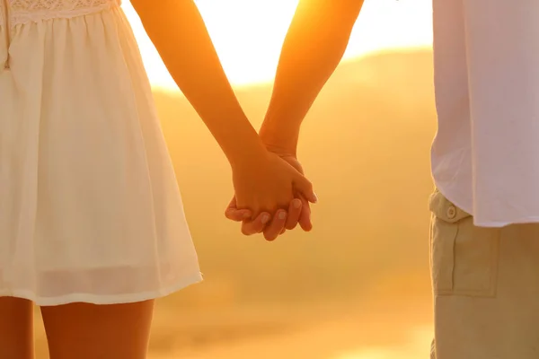 Close up de um casal de mãos dadas ao pôr do sol — Fotografia de Stock