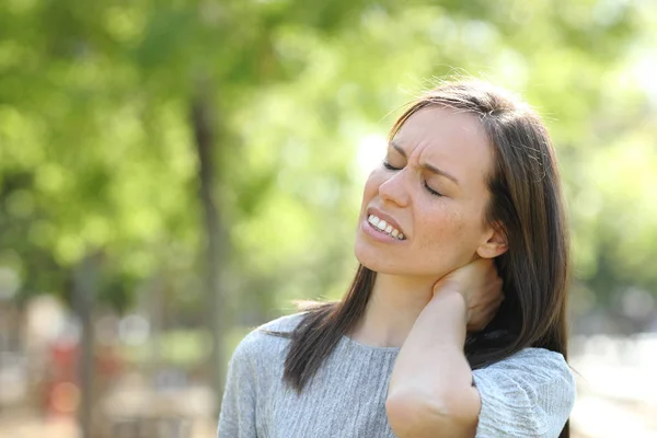 Mujer sufriendo dolor de cuello al aire libre en un parque — Foto de Stock