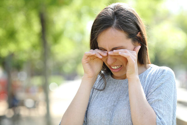 Disgusted woman rubbing her eyes in a park