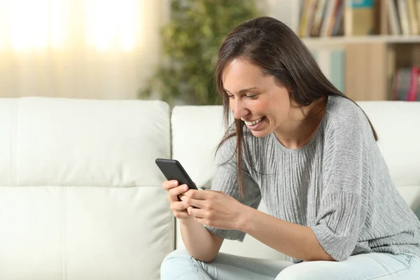 Mujer feliz en casa mensajes de texto en el teléfono — Foto de Stock