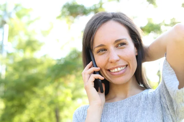 Mulher feliz chama pelo telefone em um parque — Fotografia de Stock