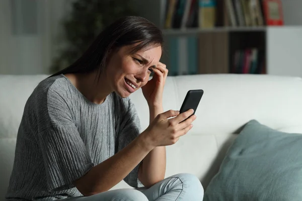Mujer triste en casa revisando el teléfono inteligente en la noche — Foto de Stock