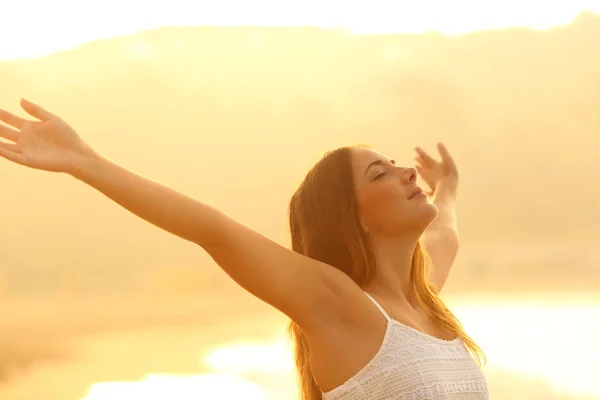 Femme détendue étirant les bras respirant l'air frais au coucher du soleil — Photo