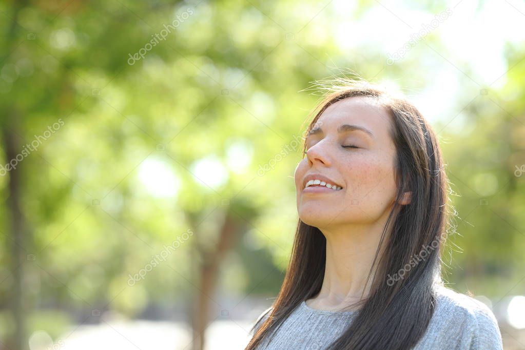 Happy woman breathing fresh air in a park or forest