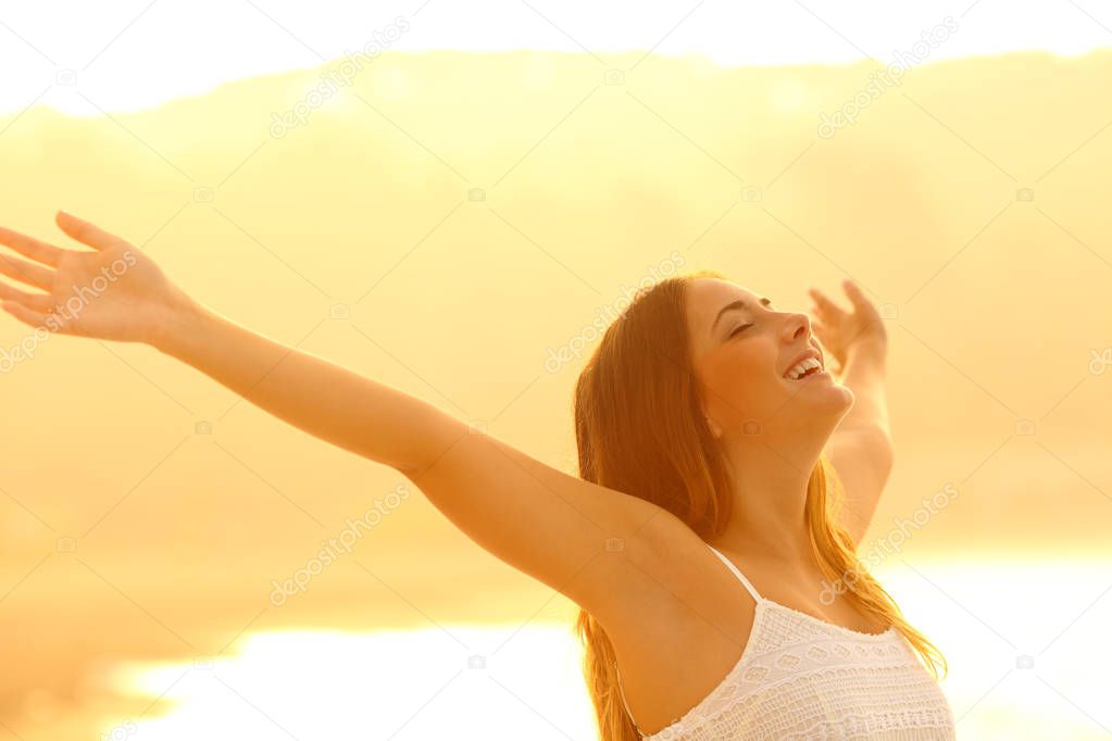 Happy woman trstching arms breathing fresh air at sunset